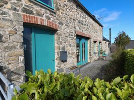 An exterior view of a stone cottage with turquoise doors and plants at The Barn in Newport