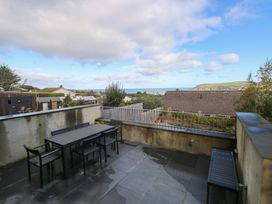An outdoor seating area with a table and chairs overlooking the sea at The Barn in Newport