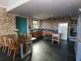 A kitchen with a dining table and refrigerator at The Barn in Newport