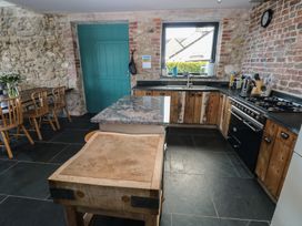 A kitchen with wooden cabinets and a stone wall at The Barn in Newport