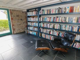 A reading room with a bookshelf and chair at The Barn in Newport