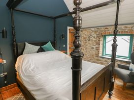 A bedroom with a four-poster bed and an armchair at The Barn in Newport