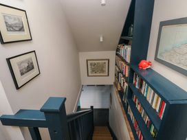 A staircase with a bookshelf and pictures at The Barn in Newport