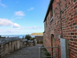A pathway leading to a gate beside a brick wall overlooking the sea at The Barn in Newport