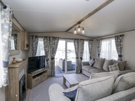 A living room featuring a sofa, television, and coffee table at Grasmoor View Lodge