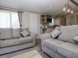 A living room with sofas and a kitchen area at Grasmoor View Lodge