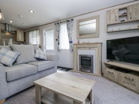 A living room with a sofa and television at Grasmoor View Lodge