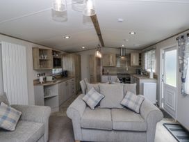 A living room with a sofa and kitchen area at Grasmoor View Lodge