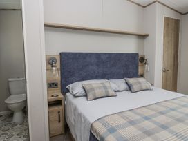 A bedroom with a bed and bedside table at Grasmoor View Lodge