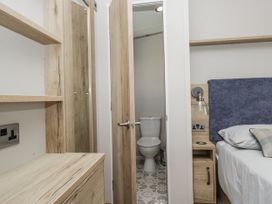 A bedroom with a toilet visible through an open door at Grasmoor View Lodge