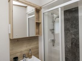 A bathroom with a mirror, sink, and shower at Grasmoor View Lodge
