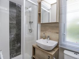 A bathroom with a shower, sink, and cabinet at Grasmoor View Lodge