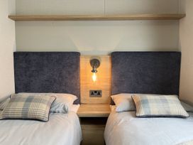 A bedroom with two beds and bedside table at Winscales Rest in Winscales