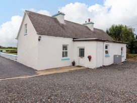 A cottage with a door and windows on a gravel driveway at The Farmhouse in Tralee, County Kerry
