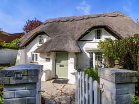 A cottage with a thatched roof and front door at Smugglers Cottage in New Milton