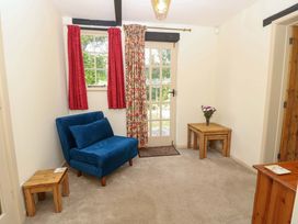 A living room with an armchair and a wooden table at Smugglers Cottage in New Milton