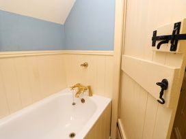 A bathroom with a bathtub and a door at Smugglers Cottage in New Milton