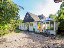 A garden with a house and a conservatory at Smugglers Cottage in New Milton