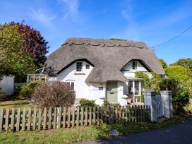 A thatched roof cottage with a fence and garden at Smugglers Cottage in New Milton