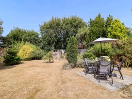 A garden with a table and chairs under an umbrella at Smugglers Cottage in Barton On Sea