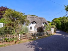 A thatched roof cottage with a garden at Smugglers Cottage Barton On Sea