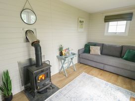 A living room with a wood stove and sofa at Seiriol Shepherds hut Ty Croes