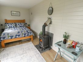A bedroom with a bed, stove and table at Seiriol Shepherds hut Ty Croes