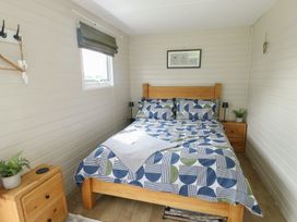 A bedroom with a bed and bedside table at Seiriol Shepherds hut in Ty Croes