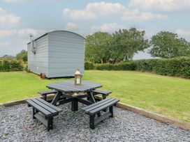 An outdoor seating area with a table and benches at Seiriol Shepherds hut Ty Croes