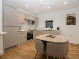 A kitchen with cabinets, stove and table at 2 Harbour Lights in Cemaes Bay