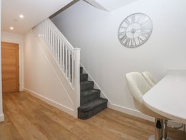 A hallway with a staircase and clock at 2 Harbour Lights in Cemaes Bay