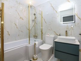 A bathroom featuring a bathtub, shower, toilet and sink at 2 Harbour Lights in Cemaes Bay