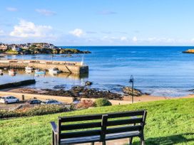 A view of a harbor with boats and a bench at 2 Harbour Lights Cemaes Bay