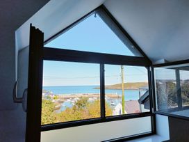 A view of a harbor with boats from a window at 2 Harbour Lights in Cemaes Bay