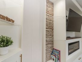 A living room with a television and books on a shelf at The Cabin in Thornton Dale