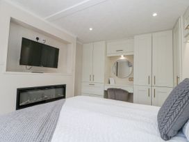 A bedroom with a bed, television, and wardrobe at The Cabin in Thornton Dale