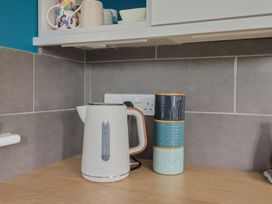 A kettle and stacked mugs on a countertop at The Roost in Whitford Nr. Colyton