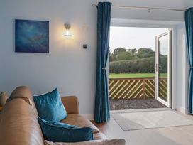 A living room with a couch and open door at The Roost in Whitford Nr. Colyton