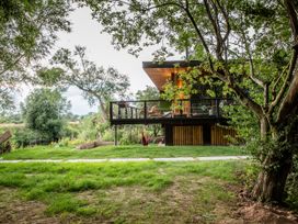 A house with a deck surrounded by trees and grass at The Red House in Farndon