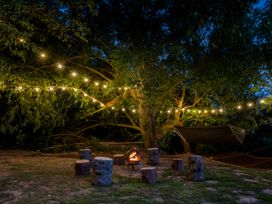An outdoor area with a fire pit and seating surrounded by string lights at The Red House in Farndon