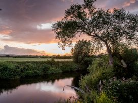A river with trees and grass under a sunset at The Red House in Farndon