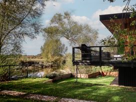 An outdoor area with a hammock and grill overlooking a river at The Red House in Farndon