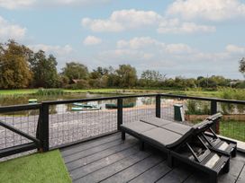 A deck with chairs overlooking a body of water at The Larch House in Farndon
