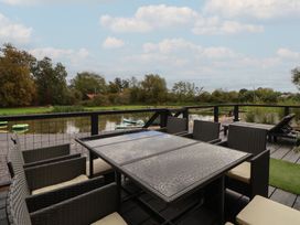 An outdoor seating area with a table and chairs overlooking a river at The Larch House in Farndon