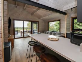 A kitchen with an island and bar stools at The Larch House in Farndon