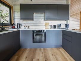 A kitchen with cabinets, sink, kettle, oven, and microwave at The Larch House Farndon