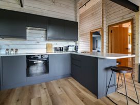 A kitchen with black cabinets and appliances at The Larch House in Farndon