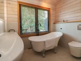 A bathroom with a bathtub and toilet at The Larch House in Farndon