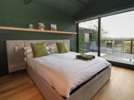 A bedroom with a bed and a view of the outdoor balcony at The Larch House in Farndon