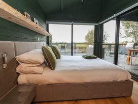 A bedroom with a bed and window overlooking an outdoor deck at The Larch House in Farndon